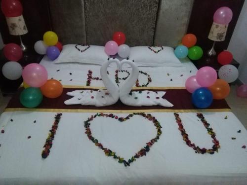 un pastel con dos corazones y globos en una cama en Horizon Hotel Apartments - الأفق للشقق الفندقية en Al Khawḑ
