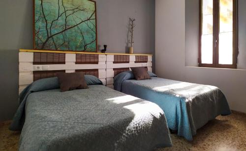 貝納薩的住宿－XALET de MUNTANYA，一间卧室设有两张床,墙上挂着一幅画