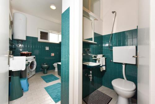 a green bathroom with a toilet and a sink at Apartments Markulin 3562 in Preko