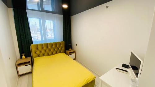 a bedroom with a yellow bed and a window at Green & White Apartament in Anykščiai