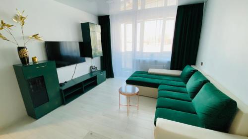 een woonkamer met een groene bank en een televisie bij Green & White Apartament in Anykščiai
