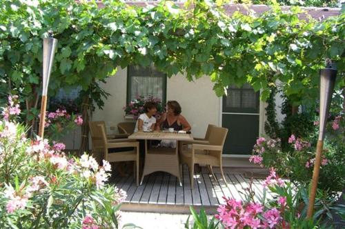 una mujer y un niño sentados en una mesa en un patio en Romantikchalet, en Breitenbrunn am Neusiedler See
