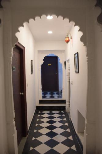 a hallway with a black door and a checkered floor at Hotel Mewari Villa PURE VEG in Udaipur