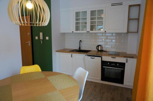 a kitchen with white cabinets and a table with chairs at Enklawa Białowieska Forest & Spa in Hajnówka