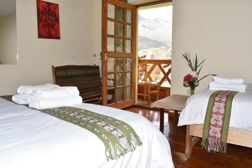 two beds in a room with a view of a mountain at Apu Lodge in Ollantaytambo