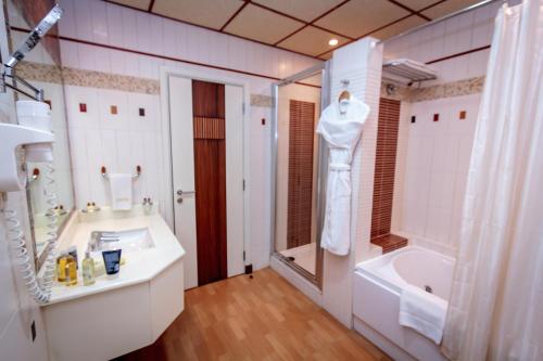 W łazience znajduje się umywalka, wanna i prysznic. w obiekcie City Center Hotel w mieście Manama