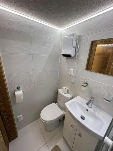 a white bathroom with a toilet and a sink at Vila Mudroň - Studio in Vysoke Tatry - Dolny Smokovec