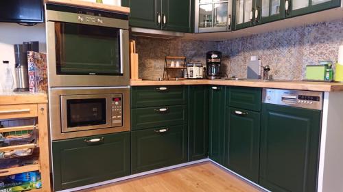 a green kitchen with green cabinets and a microwave at Malvelyns am Bodensee in Immenstaad am Bodensee