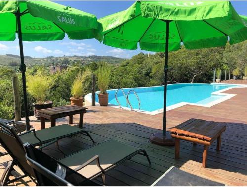 a deck with chairs and umbrellas next to a pool at Ventorrillo de la Buena Vista in Minas
