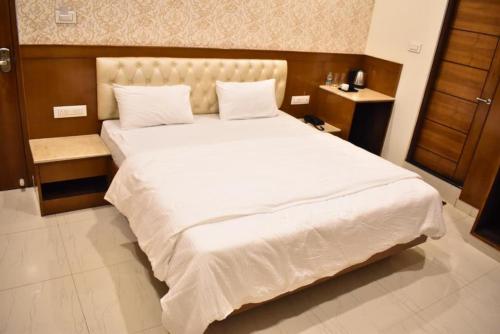 a bedroom with a large white bed with a wooden headboard at THE GRAND CORAL in Bengaluru