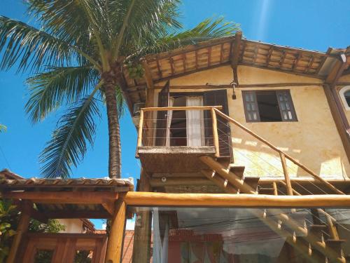 a house with a balcony and a palm tree at Chalé de Charme MANDOMAI - Suítes com Cozinha Compacta, Suítes com Cooktop e Chalé com Cozinha in Ilhabela