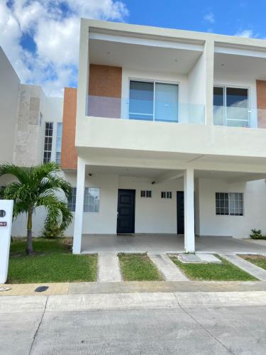 a white house with a palm tree in front of it at Casa Rosa Smart House in Playa del Carmen