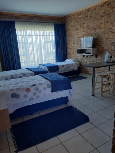 two beds in a room with a table and a tableablish at Dream lodging apartment in Vanderbijlpark