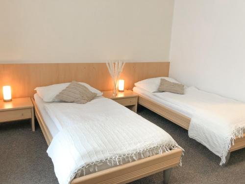 two beds in a room with two lamps on tables at Pension Ingrid in Neutal