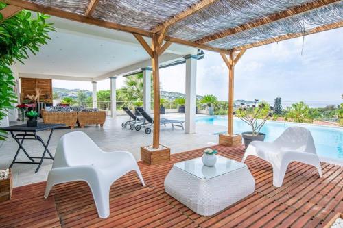 eine Terrasse mit weißen Stühlen und einem Pool in der Unterkunft Villa individuelle avec piscine privée chauffée proche commerces et plage in Porticcio