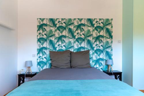 a bedroom with a blue bed with a blue and green wallpaper at D'un jour à l'autre in Banassac