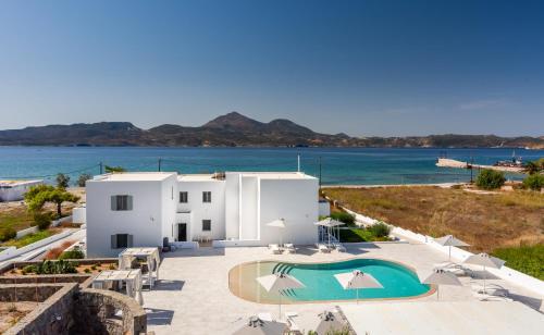 a white building with a swimming pool next to the ocean at Olea Bay Hotel in Adamas