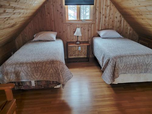 two beds in a attic bedroom with wooden walls at Chalets de l'Anse Ste Helene in Maria