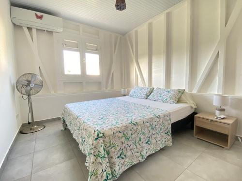 a white bedroom with a bed and a fan at Le Royal Horizon in Deshaies
