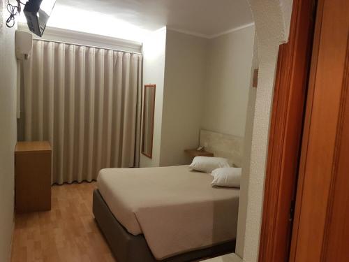 a small bedroom with a bed and a window at Hotel Nova Cidade in Amadora