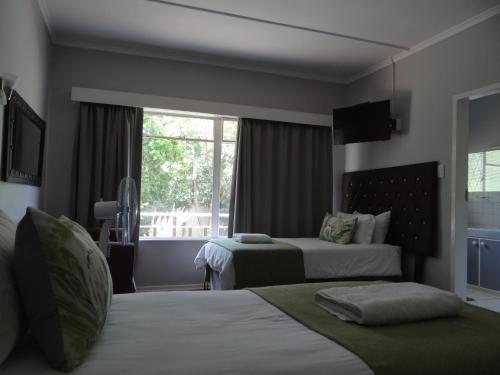 a hotel room with two beds and a window at CREDO Guest House in Bloemfontein