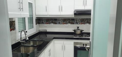 a white kitchen with white cabinets and a sink at Apartamento Marina Smir in Tetouan