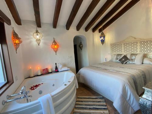 1 dormitorio con bañera junto a la cama en El Escondite de Martina, Áticos Románticos, en Setenil