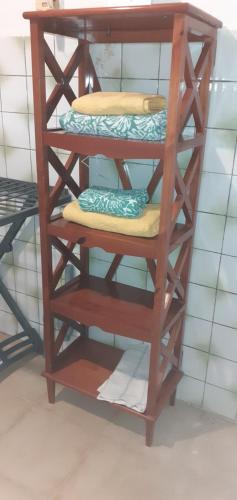 a wooden shelving unit with three tiers of towels at Bas de villa Aka Cecette in Petit-Bourg