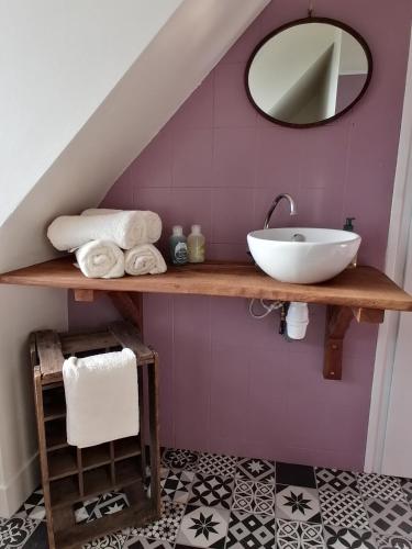 La salle de bains est pourvue d'un lavabo et d'un miroir sur un mur violet. dans l'établissement Gîte 4 pers proche plage avec jardin, à Clohars-Carnoët