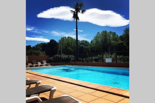 uma piscina com uma palmeira ao fundo em 2 bedrooms, 15 min walk to beach, AC, pool & fiber internet in a quiet, private gated domain 5kms to St Tropez em Cogolin