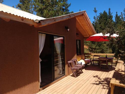 ein Haus mit einer Terrasse mit einem Tisch und einem Sonnenschirm in der Unterkunft Cabaña El Mirador de Vichuquén in Vichuquén