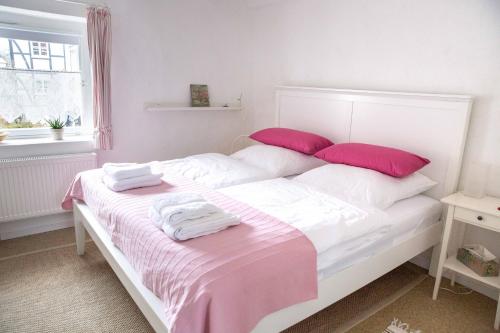 een wit bed met roze en witte lakens en kussens bij Bergische Ferienwohnung in Engelskirchen