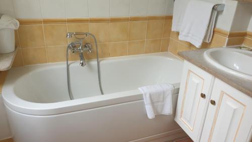 La salle de bains est pourvue d'une baignoire blanche à côté d'un lavabo. dans l'établissement Hôtel L'Hermitage, à Pernes-les-Fontaines
