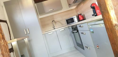 una pequeña cocina con armarios blancos y microondas en Baribal'ele en Colmar