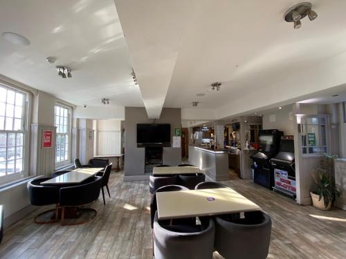 a waiting room with chairs and tables and a tv at Wendover Arms Hotel in High Wycombe