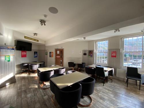 a dining room with tables and chairs and windows at Wendover Arms Hotel in High Wycombe