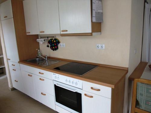 uma cozinha com armários brancos, um lavatório e um fogão em Ferienappartment Allendorf em Sundern