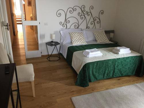 Schlafzimmer mit einem Bett mit einer grünen und weißen Bettdecke in der Unterkunft Est Locanda in San Ginesio