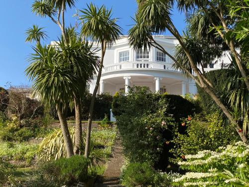 a white house with palm trees in front of it at Vomero Holiday Apartments in Torquay