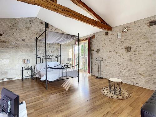 um quarto com uma cama numa parede de tijolos em GITES STE CATHERINE em Teyssode