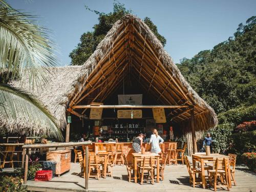 a group of people sitting at a restaurant with tables and chairs at Rio Hostel Buritaca in Buritaca