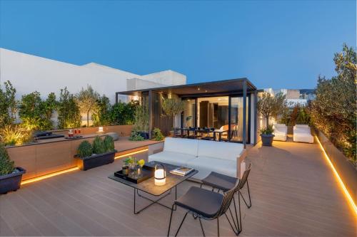 a rooftop patio with a white couch and chairs at The Newel Acropolis in Athens
