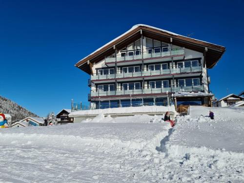 a building on top of a snow covered mountain at Bergzeit - Hotel & Appartements in Oberjoch