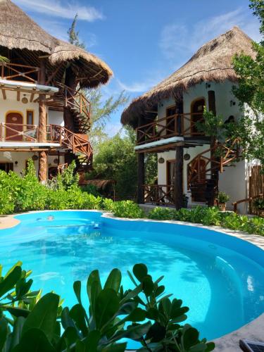 een resort met een zwembad en twee hutten bij Casa Hridaya Hotel Boutique in Holbox Island