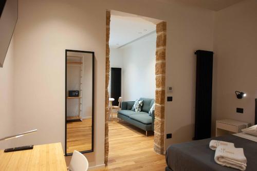 a bedroom with a mirror and a blue couch at Palazzo al Carmine in Monreale
