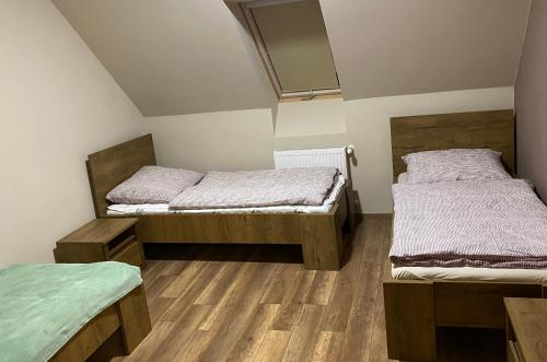two beds in a room with wooden floors at BarAnd Apartman in Eger