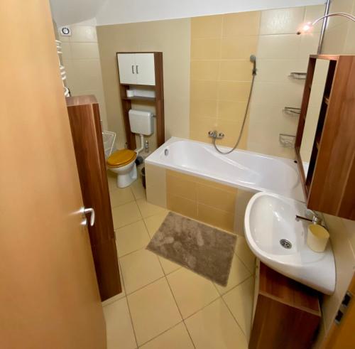 a bathroom with a tub and a toilet and a sink at BarAnd Apartman in Eger