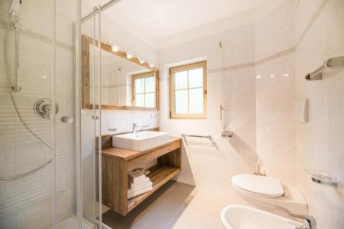 ein Bad mit einem Waschbecken, einem WC und einer Dusche in der Unterkunft Boutique Hotel Eggele in Innichen