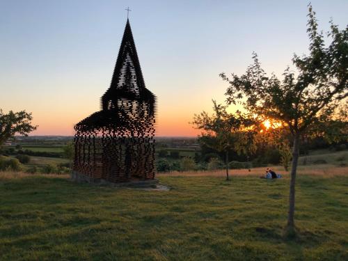 a sculpture in a field with the sunset in the background at Le fond d'Or in Borgloon