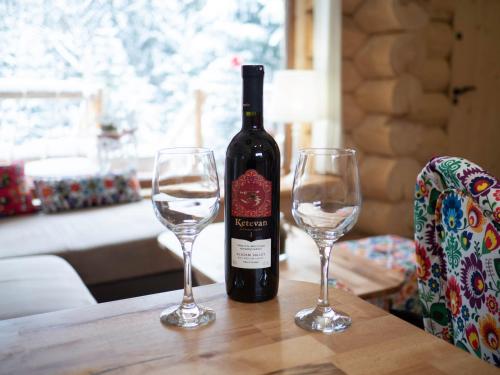 a bottle of wine sitting on a table with two wine glasses at Zagroda Krowiarki Chochołów in Chochołów